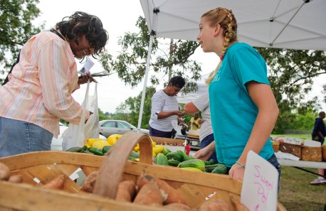 UNCG photo by Chris English - 09/20/2011 - UNCG communication studies student Hannah Harris, right, works with customers at the Warnersville Farmers Market on Tuesday September 20, 2011. The neighborhood has many low-income residents who don’t have reliable transportation to get to a grocery store, so it is difficult for them to find fresh fruits and vegetables. The communications Studies department is working on easier access to healthy foods to areas called food deserts.