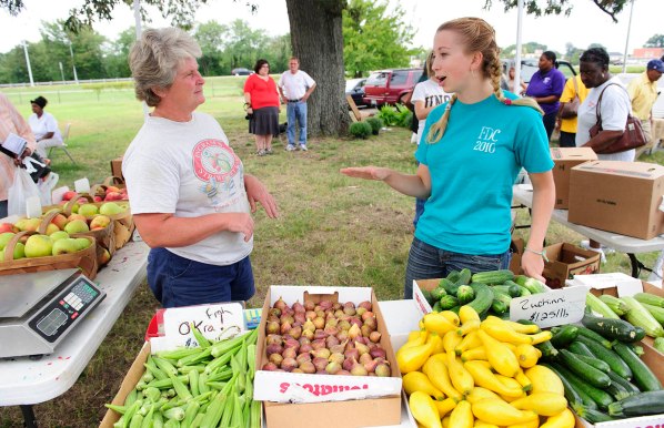 UNCG photo by Chris English - 09/20/2011 - UNCG communication studies student Hannah Harris, right, talks with a vender at the Warnersville Farmers Market on Tuesday September 20, 2011. The neighborhood has many low-income residents who don’t have reliable transportation to get to a grocery store, so it is difficult for them to find fresh fruits and vegetables. The communications Studies department is working on easier access to healthy foods to areas called food deserts.
